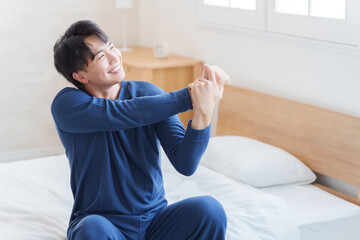 朝ベッドから起きてストレッチする男性