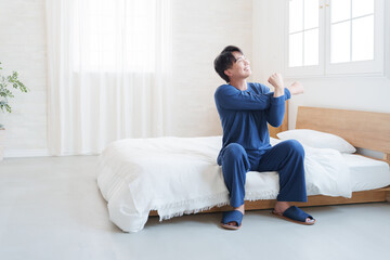朝ベッドから起きてストレッチする男性