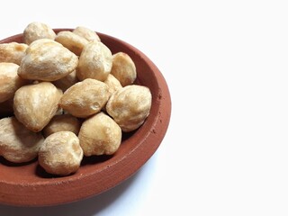 top view of candlenuts in a clay bowl, isolated on a white background
