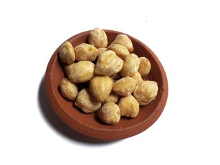 top view of candlenuts in a clay bowl, isolated on a white background