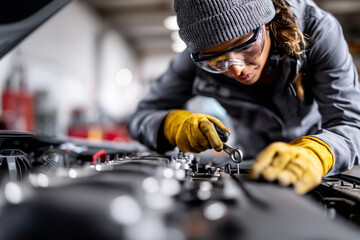 Female mechanic inspecting car engine, focus on hands and tools, small business garage atmosphere, 