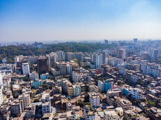 Fototapeta premium Aerial view of a modern city with a highway running through it. Aerial view of Chittagong City with buildings, roads, and trees on a sunny day. Aerial View Cityscape of Chittagong City Bangladesh.