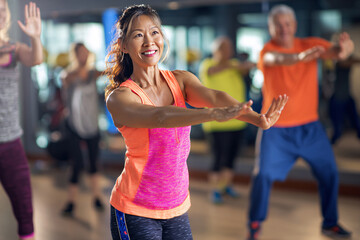 A middle-aged woman in bright sportswear conducts fitness classes for other women in the club