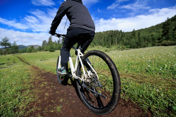 Fototapeta premium Riding mountain bike on grassland forest mountains