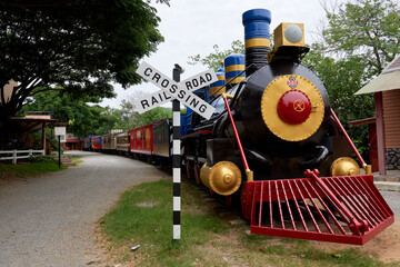Vintage Steam Locomotive Parked at a Railway Crossing Surrounded by Greenery