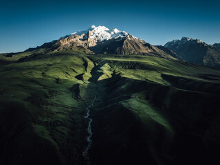Aerial view of beautiful high altitude snow capped mountains and forest grassland landscape in China