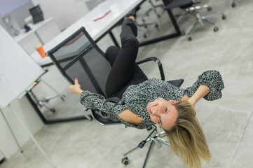 Caucasian woman having fun and lying on office chair. 