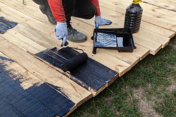 Man is painting a wooden deck with a roller