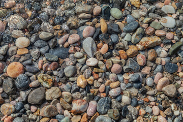Rocky beach with a lot of rocks and water. The rocks are of different sizes and colors, and the water is calm. The scene has a peaceful and serene mood, with the rocks and water creating a beautiful
