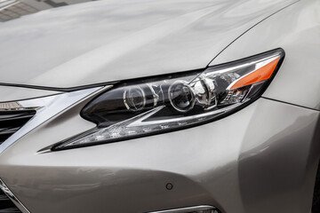 The headlight of a silver car is lit up