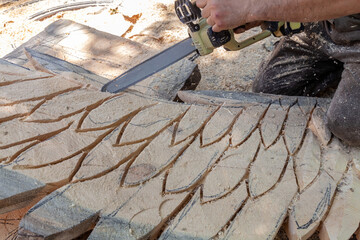 Man is cutting a piece of wood with a saw