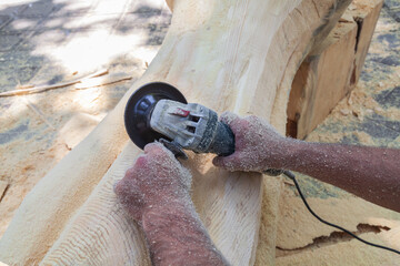 Man is sanding a piece of wood with a power tool