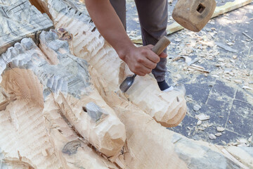 Man is carving a piece of wood with a chisel