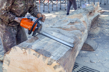 Man is cutting a log with a chainsaw