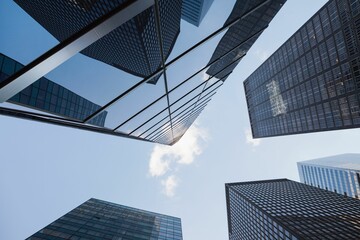 Office glass towers forming canyon at street level, reflecting sunlight on grid patterns
