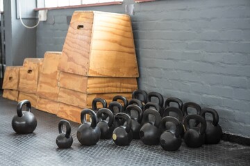 Group of kettlebells is filling flat design gym corner with rubber mat, showing stacked plyo boxes