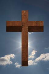 Flat design wooden Christian cross is rising against blue sky with sunburst and clouds, copy space