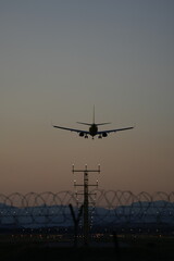 A commercial airplane approaches a runway during dusk