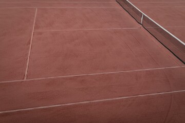 Clay tennis court is being shown in flat design with taut net posts and faded lines