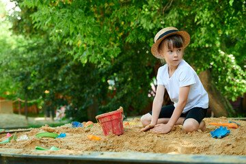 A six-year-old girl plays in a sandbox