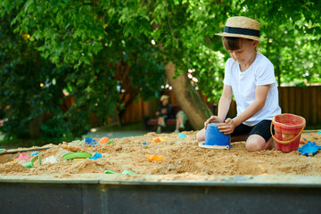A six-year-old girl plays in a sandbox