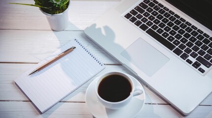 Laptop with book and coffee cup on table