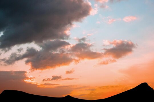 Fototapeta Flat design illustration showing rolling desert sand dune silhouettes under glowing sunset clouds