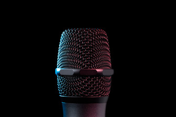 Close-up of microphone in studio or concert performance on stage, on black background.