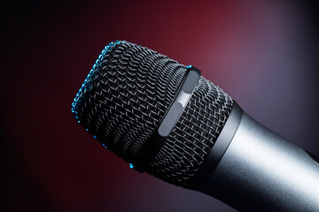 Close-up of microphone in studio or concert performance on stage, on black background.