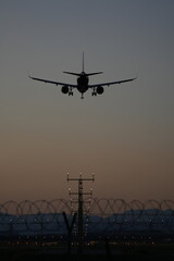 A commercial airplane approaches a runway during dusk