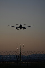 A commercial airplane approaches a runway during dusk