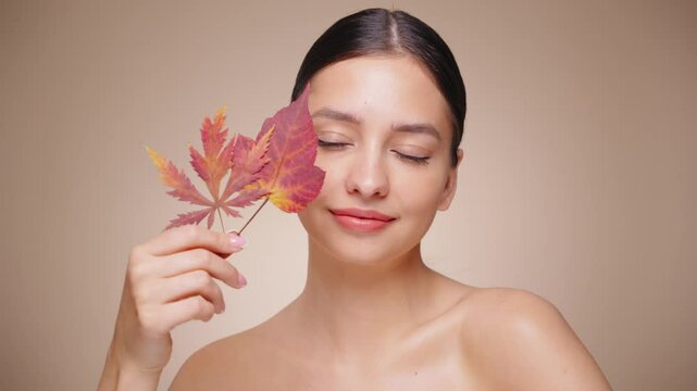 Portrait of beautiful young woman with autumn leafs. Healthy clean fresh skin natural make up beauty eyes. Slow motion video