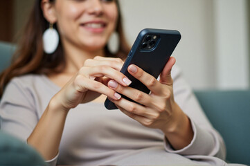A woman sitting on a couch looking at her phone.