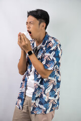 Young asian man wearing blue summer shirt is suffering sore throat and coughing holding his neck...