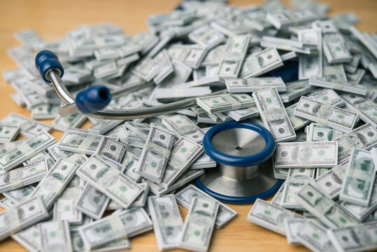 Doctor stethoscope drowning in heap US dollar banknotes. Medical debt, healthcare, expenses, cost of living, health and life insurance, money risk management, inflation crisis and so on concept.