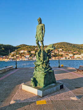 Odysseus Statue in Ithaca island,  with colorful Ionian houses in the background and the bay of  Vathy, Ithaca island, the island home of the hero Odysseus, Greece 