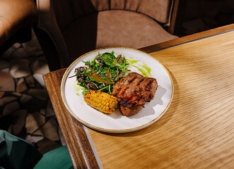 Delicious grilled steak with corn and salad at a cozy restaurant setting