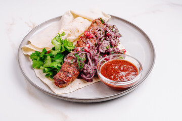 Savory grilled kebabs with fresh herbs and spicy sauce served on a plate