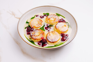 Creamy dessert with pancakes, berry sauce, and green garnish