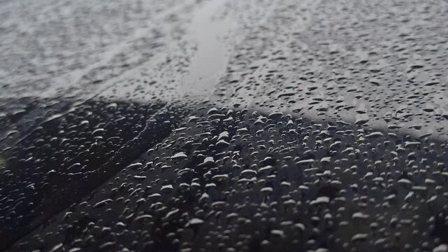 ight drizzle on a car window creates soft, wandering trails of water, blending movement and stillness in a calm, reflective driving moment