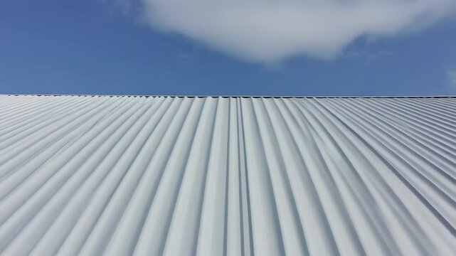 Damaged metal roof panels requiring repair under blue sky