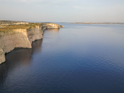 Aerial view of the rugged coastline with cliffs meeting the deep blue sea, where the land's edge kisses the horizon, Munxar, Munxar, Malta.