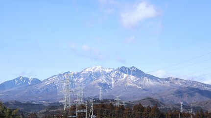 A beautiful snowy mountain range behind the transmission towers in Japan