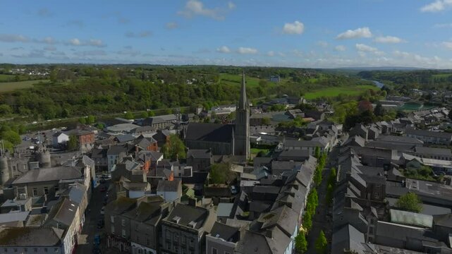 Enniscorthy, County Wexford, Ireland, April 2025. Drone panoramic aerial establishing pullback centers church overlooking lush green hills and quaint village town.