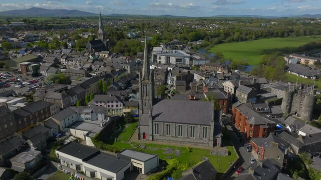 St. Mary's Church, Enniscorthy, County Wexford, Ireland, April 2025. Drone establishing sideview of church graveyard with lush green lawns and historic town buildings.