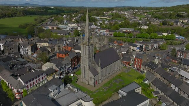 St. Mary's Church, Enniscorthy, County Wexford, Ireland, April 2025. Drone medium establishing orbit clockwise from side of building with graveyard to front tower then showcasing shadow edge.
