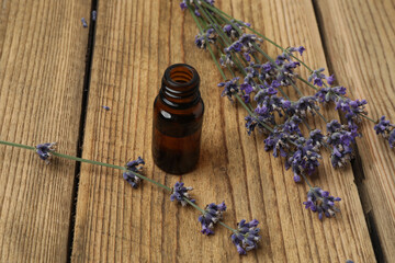 Bottles with lavender oil, lavender on wooden background