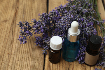 Bottles with lavender oil, lavender on wooden background