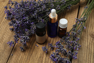 Bottles with lavender oil, lavender on wooden background