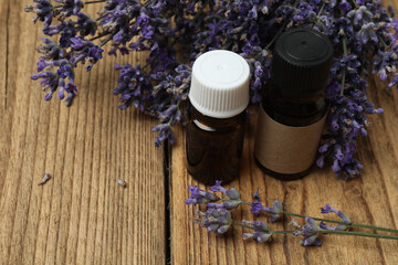 Bottles with lavender oil, lavender on wooden background